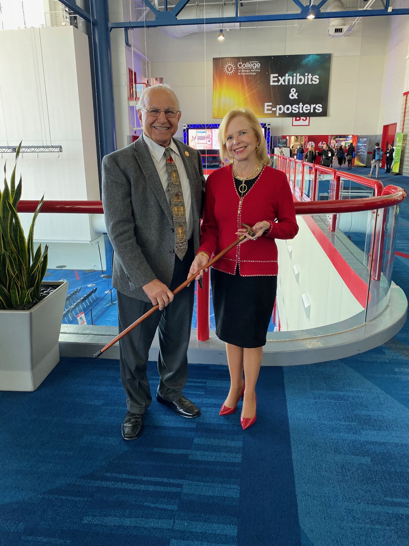 Dana Wallace holding the ACAAI Gold-Headed Cane alongside a colleague